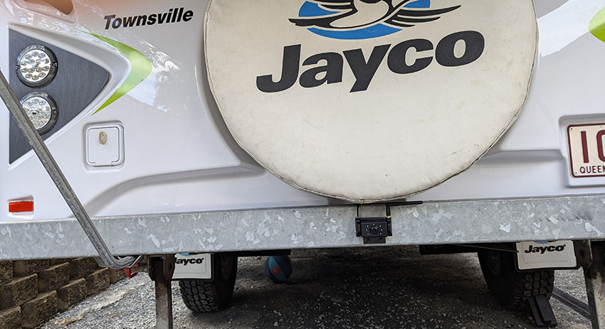 Image of an Australian tent trailer with a reversing camera fitted to the rear bumper just below the spare wheel. This camera is powered by a 12 volt DC circuit connected to the tow car's battery circuit.